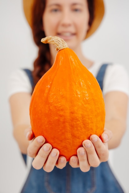 Kleine oranje pompoen in de handen van een wazige boer is een verticaal concept van biologisch voedsel