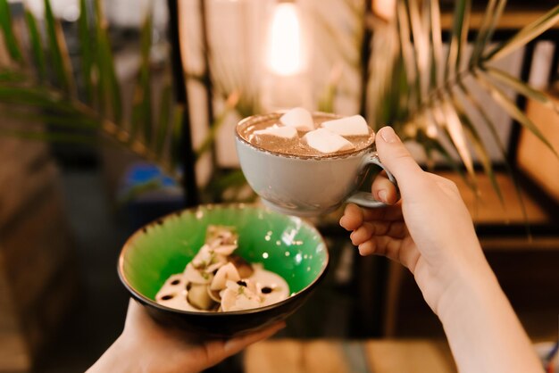 Kleine pannenkoeken in een bord met bessen en zelfgemaakte zure room met een kopje cacao met marmelade desserts in het café kindermenu selectieve focus