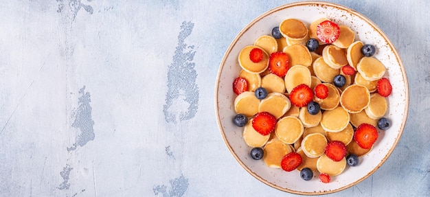 Kleine pannenkoeken met aardbeien en bosbessen als ontbijt. Bovenaanzicht.