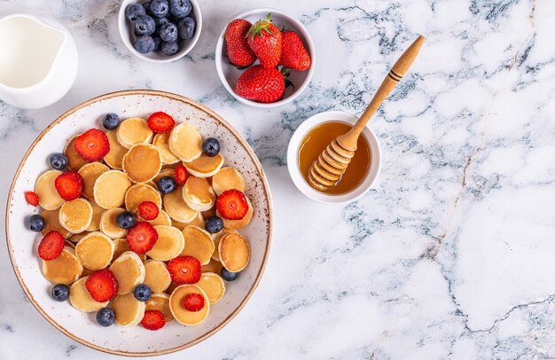 Kleine pannenkoeken met aardbeien en bosbessen als ontbijt. Bovenaanzicht.