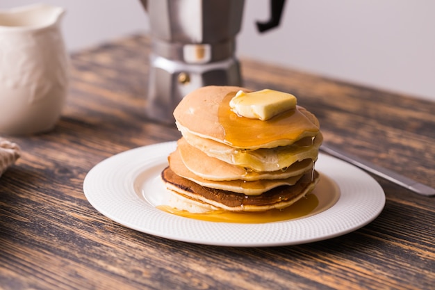 Kleine pannenkoeken met ahornsiroop en boter op houten tafel. ontbijt concept.