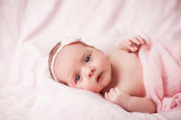 Kleine pasgeboren baby in een roze pak op een roze achtergrond. Moederschap.