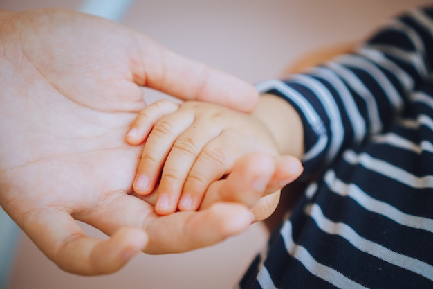 Kleine pasgeboren baby's voeten op vrouwelijke hartvormige handen Gelukkig familieconcept