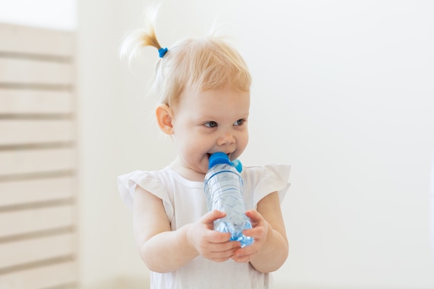 Kleine peuter babymeisje met fles water thuis