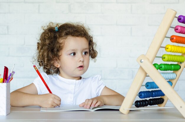 Kleine peuter meisje wiskunde leren. kind rekent op de rekeningen. ontwikkeling, opvoeding, onderwijs en opleiding van kinderen.