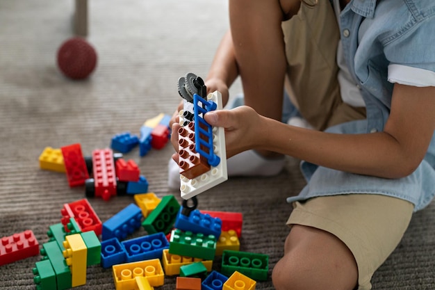 Kleine peuterjongen die thuis met kleurrijke plastic blokken speelt en creatieve spelverbeelding bouwt