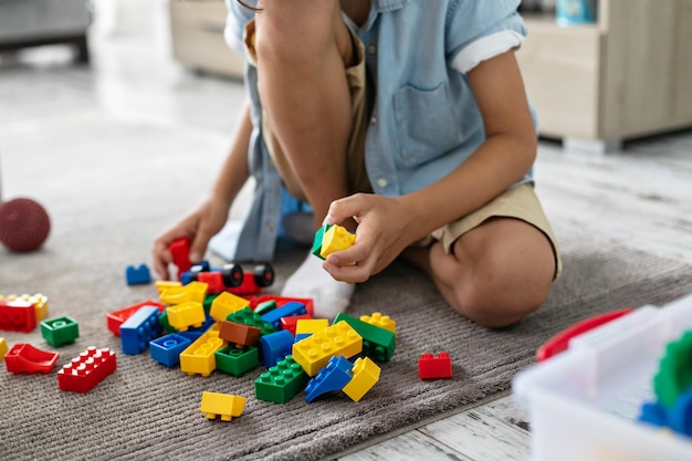 Kleine peuterjongen die thuis met kleurrijke plastic blokken speelt en creatieve spelverbeelding bouwt