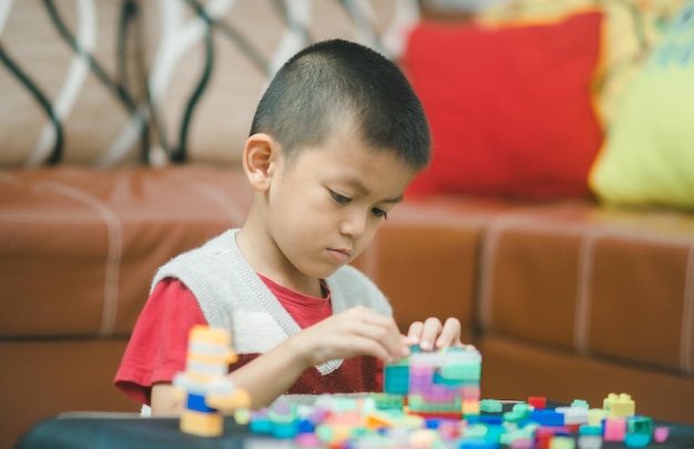 Kleine peuterjongen die thuis met Lego-treinblokken speelt tijdens de quarantaine-isolatieperiode tijdens een pandemie