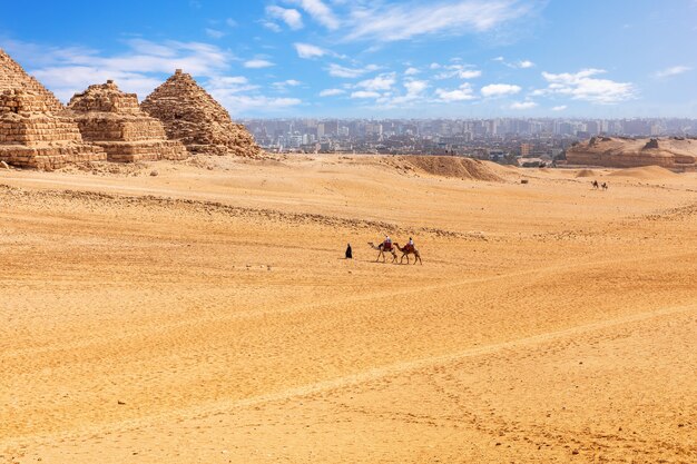 Kleine piramides van Menkaure-koninginnen en kamelen in de woestijn van Giza.