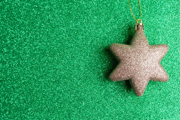 Kleine plastic kerstster en glitter op een groene ondergrond met glitter. selectieve aandacht.