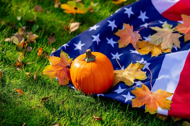 Kleine pompoen en esdoorn bladeren met USA vlag op groen gras in een tuin