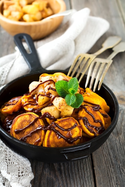 Kleine pompoenpannekoeken met chocoladesaus in pan op de oude wijnoogst