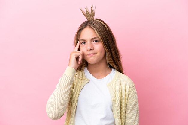 Kleine prinses met kroon geïsoleerd op roze achtergrond denken een idee