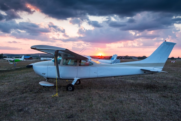 Kleine privévliegtuigen geparkeerd op het vliegveld bij een schilderachtige zonsondergang