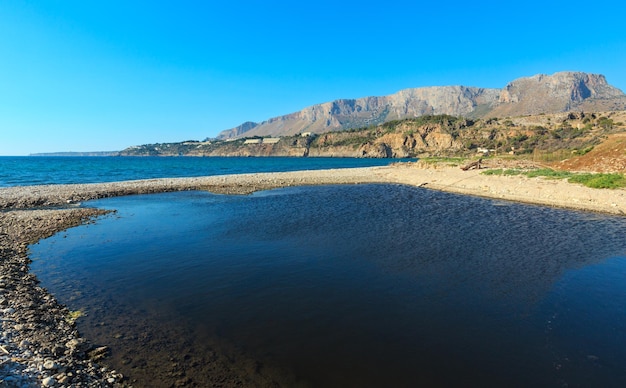 Kleine rivier mondt uit in zee op kiezelstrand