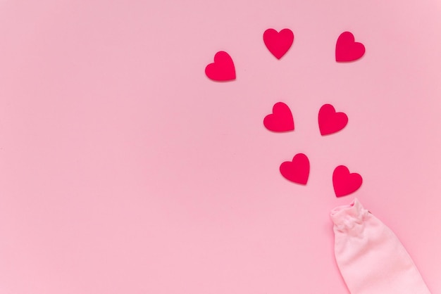 kleine rode harten vliegen uit zakje op roze achtergrond Valentijnsdag concept plat lag