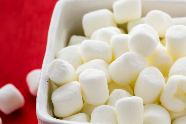 Kleine ronde witte marshmallows op rode pagina's.