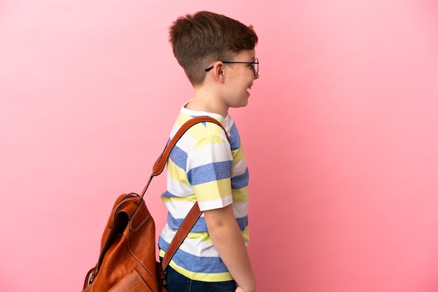 Kleine roodharige blanke jongen geïsoleerd op roze achtergrond lachen in laterale positie