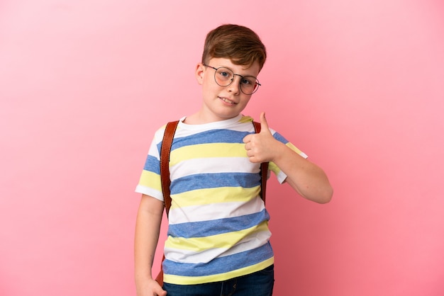 Kleine roodharige blanke jongen geïsoleerd op roze achtergrond met een duim omhoog gebaar