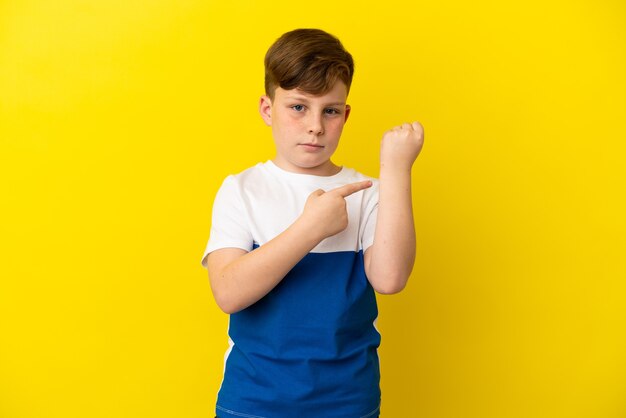 Kleine roodharige jongen geïsoleerd op een gele achtergrond die het gebaar maakt om te laat te komen