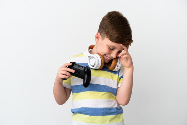 Kleine roodharige jongen met een gamepad geïsoleerd op een witte achtergrond lachen