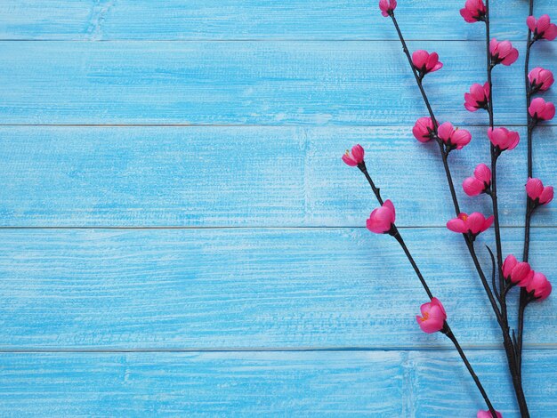 Kleine roze bloesem bloemen met bruine tak op blauwe houten achtergrond met kopie ruimte voor bruiloft of Valentijnsdag wenskaart.