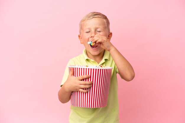 Kleine Russische jongen die popcorn eet in een grote kom over geïsoleerde achtergrond