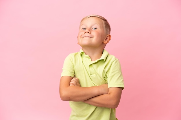 Kleine Russische jongen geïsoleerd op roze achtergrond die twijfels gebaar maakt terwijl hij de schouders optilt