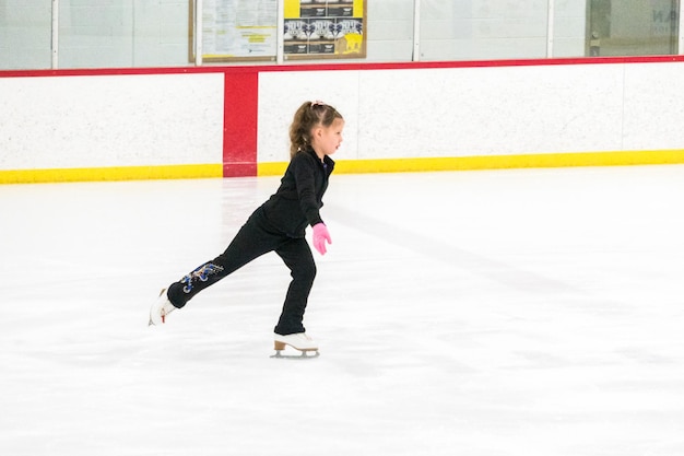 Kleine schaatser oefent haar elementen tijdens de ochtendkunstschaatsoefening.