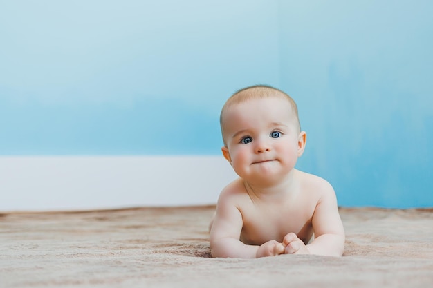 Kleine schattige baby die op de buik ligt en de ontwikkeling van het hoofd vasthoudt