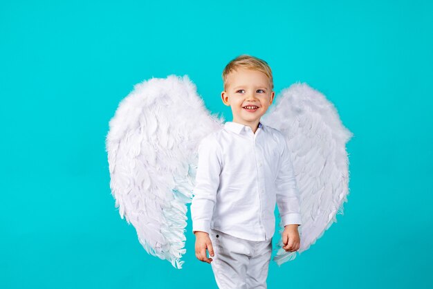 Foto kleine schattige babyjongen met blond lang met witte engelenvleugels.