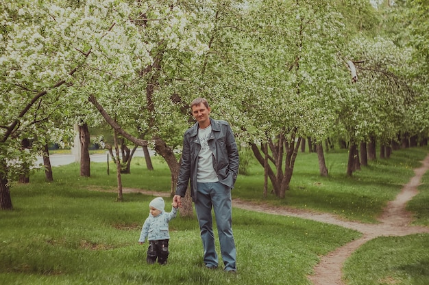 Kleine schattige babyjongen met zijn vader wandelen in het voorjaar park buiten.