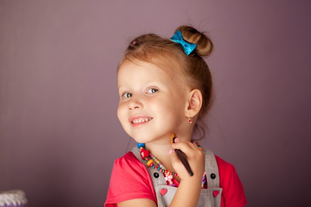 kleine schattige blonde lachend drie jaar geleden met een spiegel met een set van cosmetica en borstels