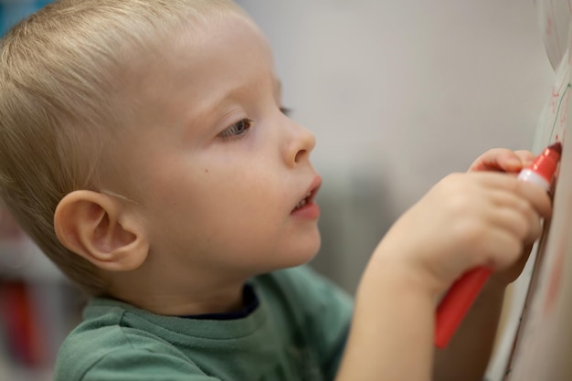 Kleine schattige jongen die leert tekenen met een stift op de tekentafelx9