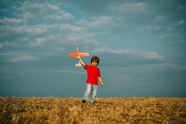 Kleine schattige jongen die met een speelgoedvliegtuig speelt Het concept van kindvriendelijkheid en kindertijd Kinderen rennen