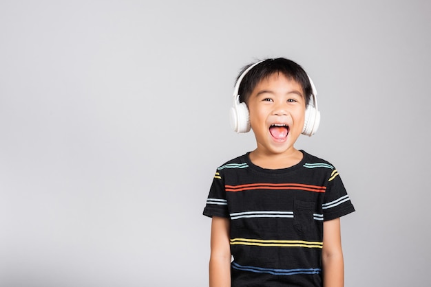 Kleine schattige jongen luistert muziek in een draadloze koptelefoon