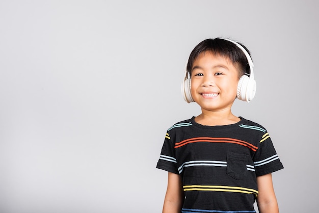 Kleine schattige jongen luistert muziek in een draadloze koptelefoon