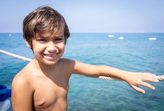 Kleine schattige jongen op zee pier genieten van vakantie