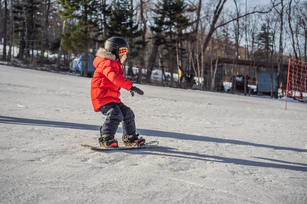 Kleine schattige jongen snowboarden Activiteiten voor kinderen in de winter Wintersport voor kinderen Lifestyle