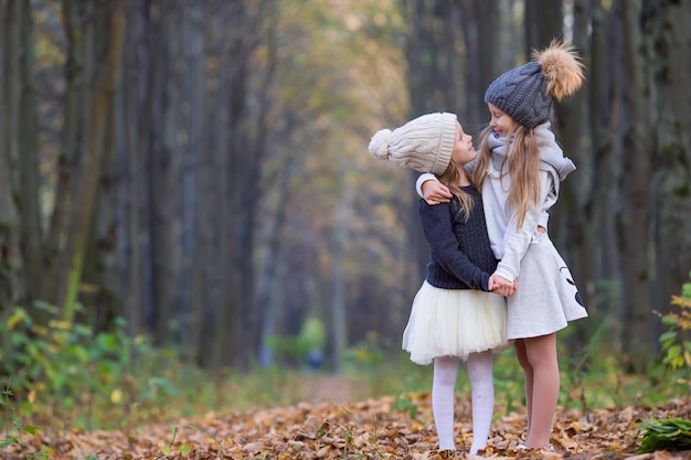 Kleine schattige meisjes buiten op warme zonnige herfstdag