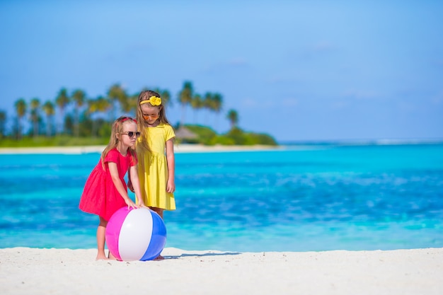 Kleine schattige meisjes die op strand met luchtbal spelen