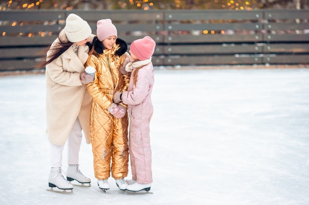 Kleine schattige meisjes met haar moeder schaatsen op de ijsbaan