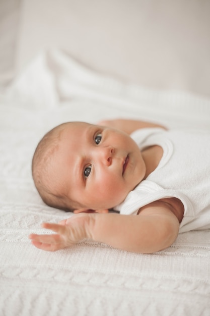 Kleine schattige pasgeborene ligt op het bed. Baby.