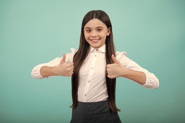 Kleine schoolmeisje student Portret van een gelukkig casual tiener kind meisje duimen opdagen en glimlachen