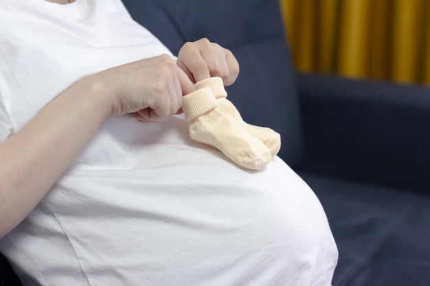 Kleine sokjes voor de ongeboren baby op de buik van zwangere vrouw