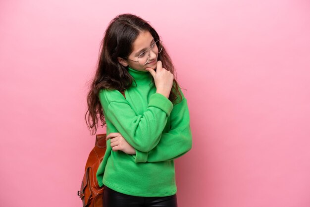 Kleine student meisje geïsoleerd op roze achtergrond op zoek naar kant