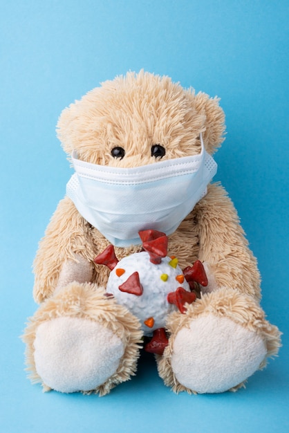 Kleine teddybeer in medisch masker met model van coronavirus