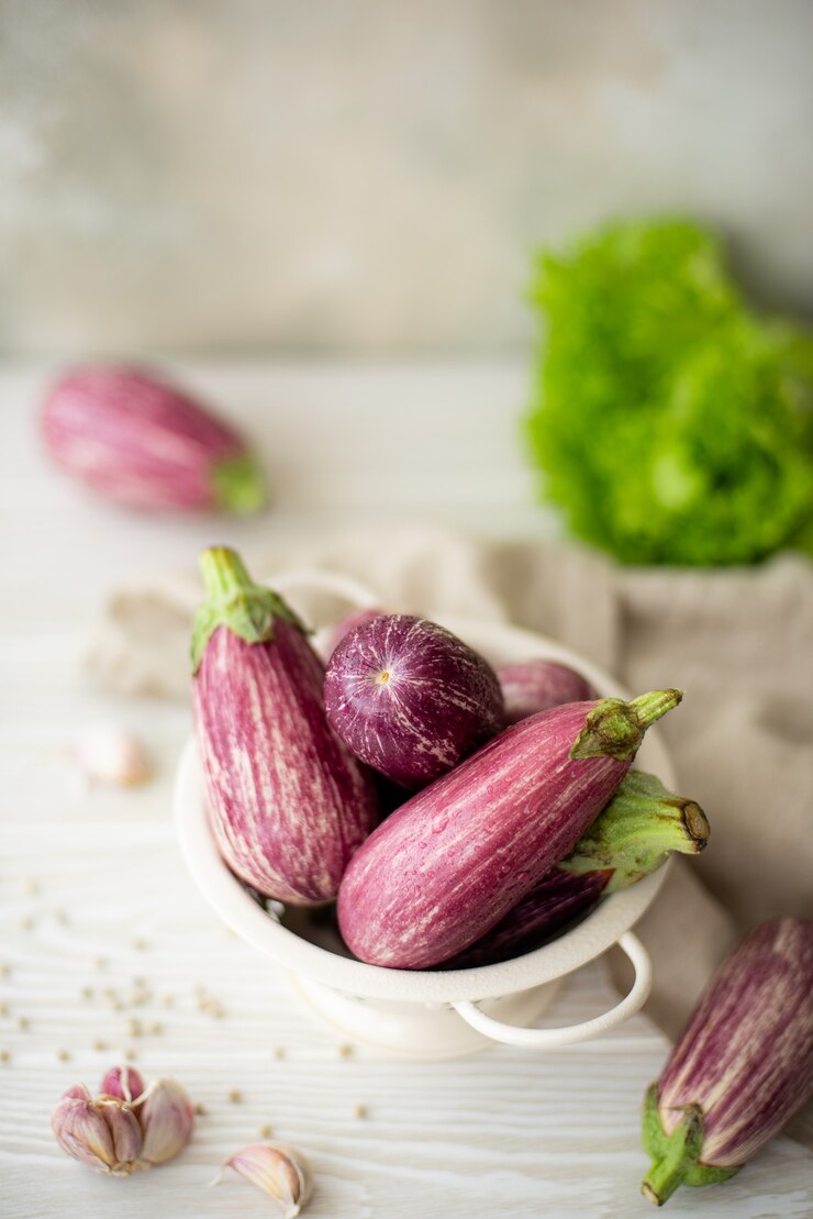 Kleine verse gestreepte aubergine met greens op een witte tafel