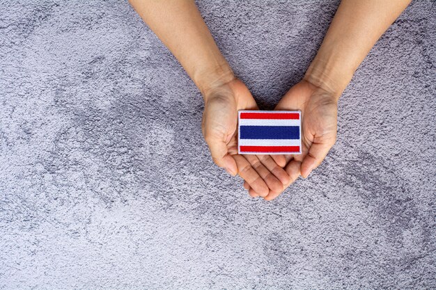 Kleine vlag van thailand in een hand. liefde, zorg, bescherming en veilig concept.