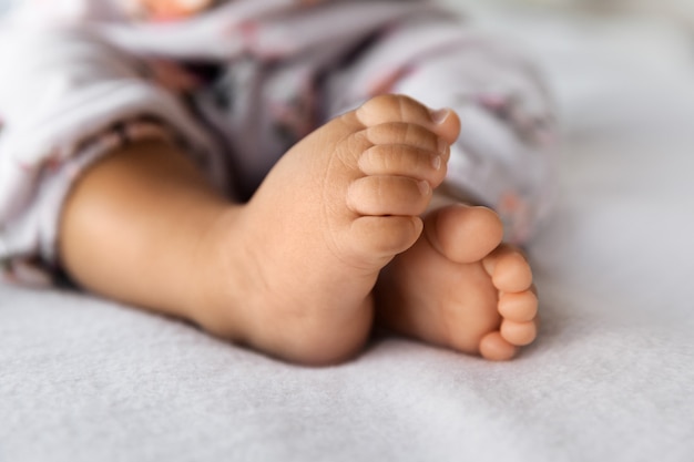 Kleine voeten van babymeisje ontspannen op het bed in een seldctive focus, babyhood concept